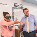 Teacher in classroom with student wearing virtual reality goggles.