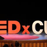 Large letters spelling TED x CU appear on a stage