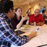 Scholars sit around a table and work collaboratively