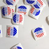 A roll of voting stickers next to a sign reading "voting day"