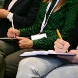 Attendees listen in and take notes during a speaker session
