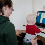 A woman at the computer with her baby on her lap