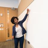 A woman writing on a dry erase board