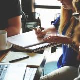 Group of people work together at table with laptops, coffee, notebooks