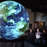 People observe a giant glowing Earth globe