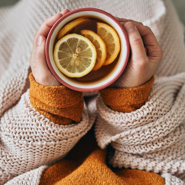 person drinking a cup of hot tea with lemon