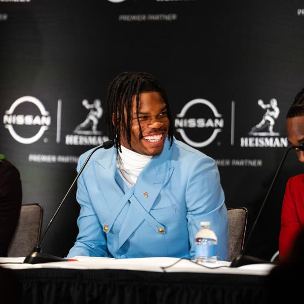 Travis Hunter sits at a table, smiling and wearing a powder blue suit.