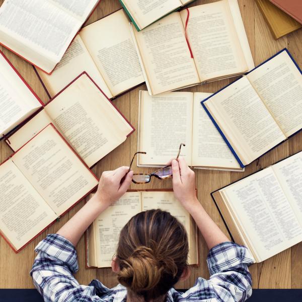 Woman seen from above looks down at books strewn across a table