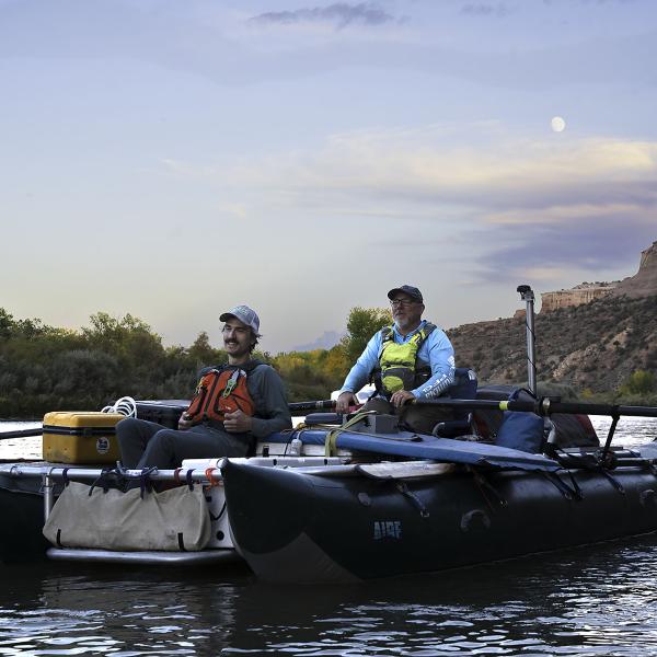 Two researchers sit on a boat with equipment.