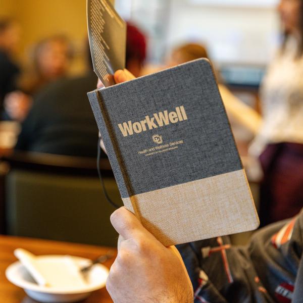 employee holding a WorkWell booklet
