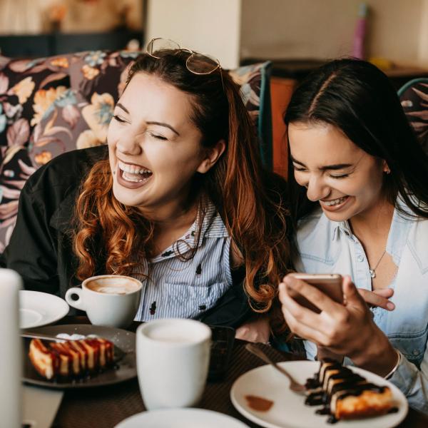 two people laughing over coffee and dessert