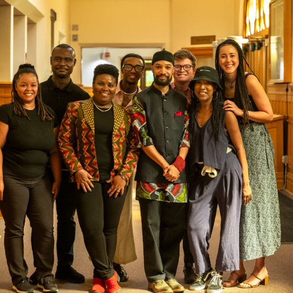 CAAAS Director Reiland Rabaka and seven other people surrounding him stand as a group in a hallway, posing for the camera with smiles.