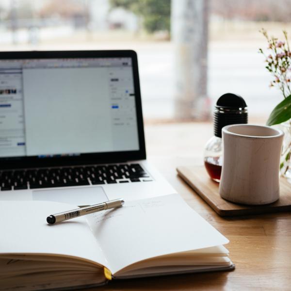 desk with laptop, notebook and cup of coffee