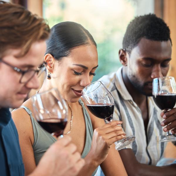 Three people sniff glasses of red wine