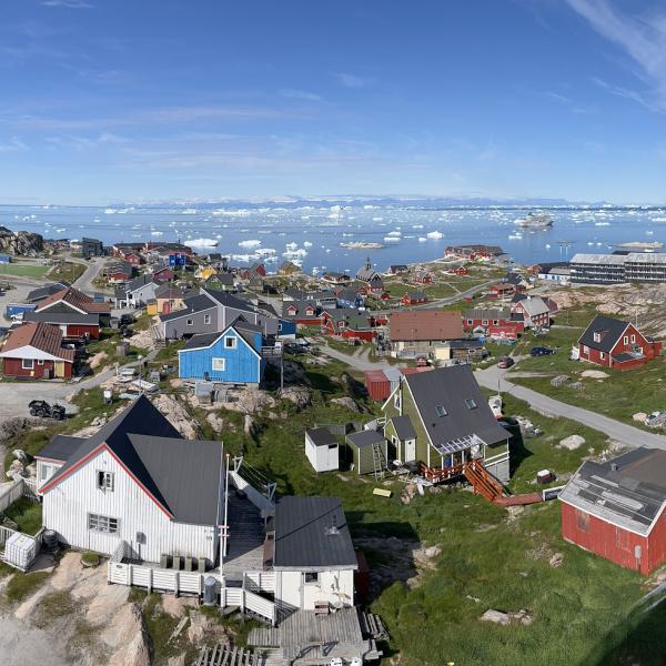 Sweeping views of Ilulissat, Greenland, show colorful buildings and many icebergs.
