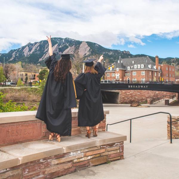 two graduate in commencement regalia