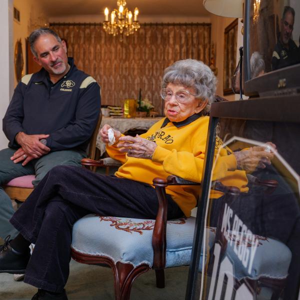 Chancellor Justin Schwartz looks at and listens to Peggy Coppom, both seated, during a living room chat.