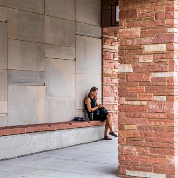 Student studying on a covered patio bench
