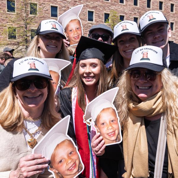 Graduate and family pose with a cutout photo from kindergarten graduation