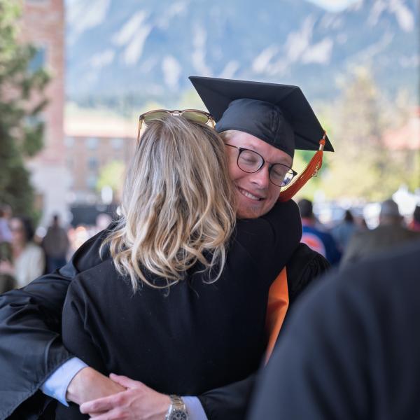 Graduate and family member hug after the ceremony