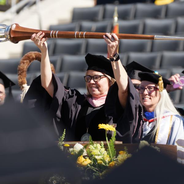 Commencement Marshal Leigh Holman raises the mace above her head to start the ceremony