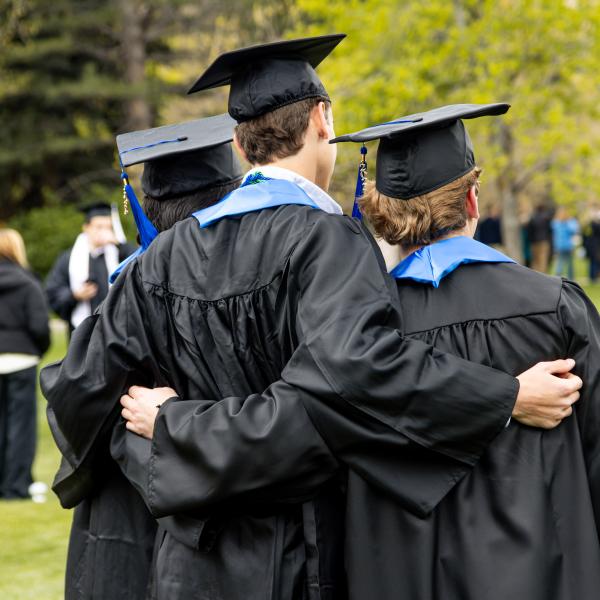 graduates standing arm in arm