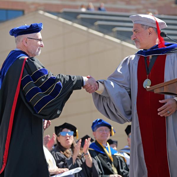 Provost Russ Moore and Chancellor Justin Schwartz shake hands