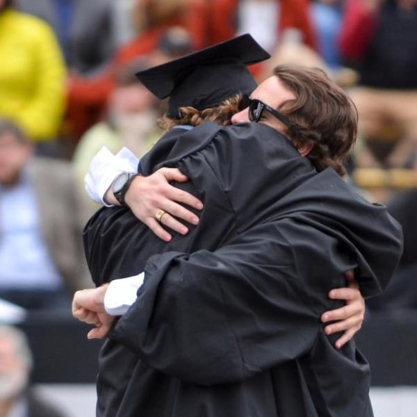 two graduates hugging after commencement ceremony