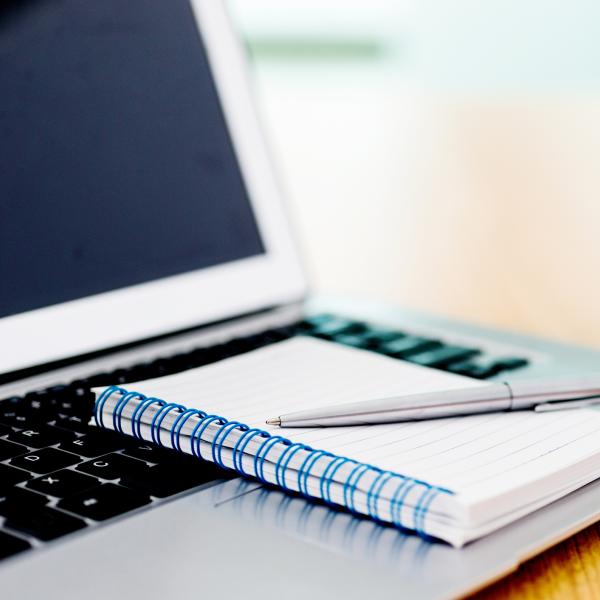 notebook and pen with a laptop