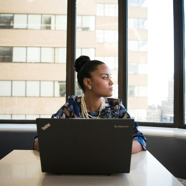 Employee sitting in front of a computer, looking out the window.