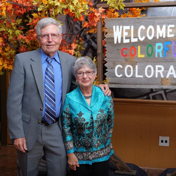 Terry and Charlotte Quarton in front of a 'Welcome to Colorful Colorado' sign