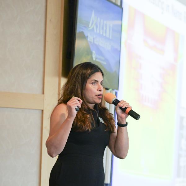Woman speaking into microphone at a business pitch event