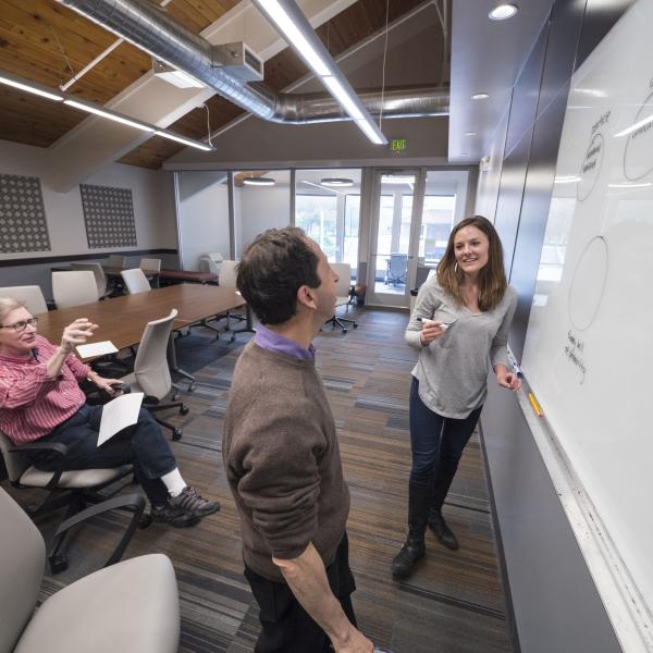 A student and professors in front of a white board.
