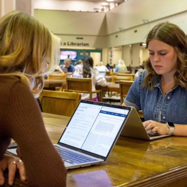 Students studying at tables in the library.