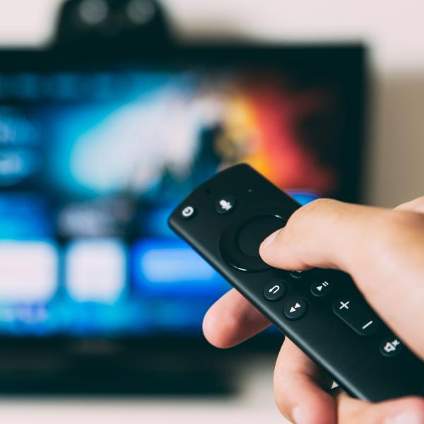 person pointing a remote control at a TV
