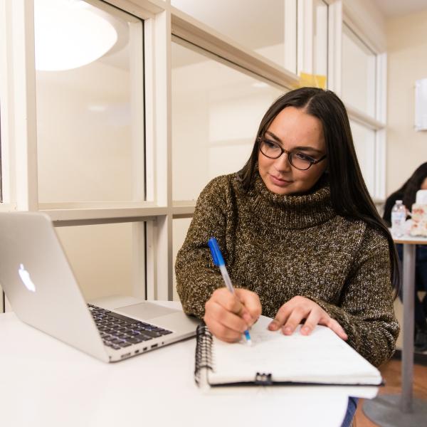 Female student writing in a notebook.