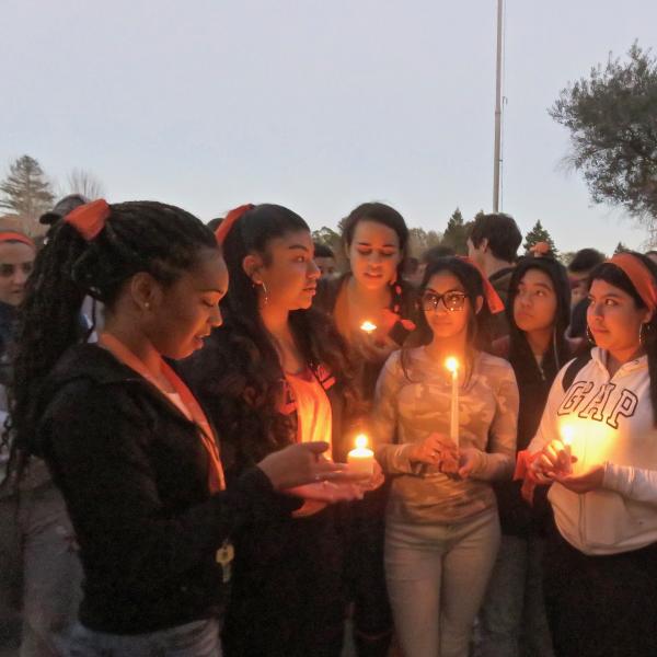 Students stand over a candle at a vigil after the Parkland High School shooting