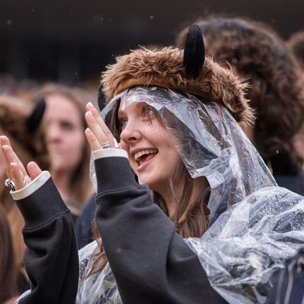 A fan wears a clear rain poncho with a plushy buffalo hat on her head.