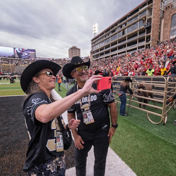 Chancellor Justin Schwartz and Gina LaFrazza take a selfie on the field. (Glenn J. Asakawa/University of Colorado)
