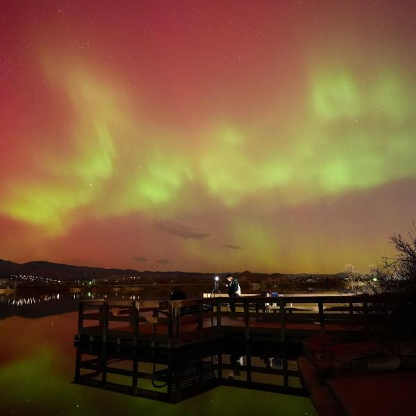 A dock on a lake seen at night with the sky glowing above it