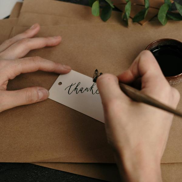 Someone writing thank you on a card.