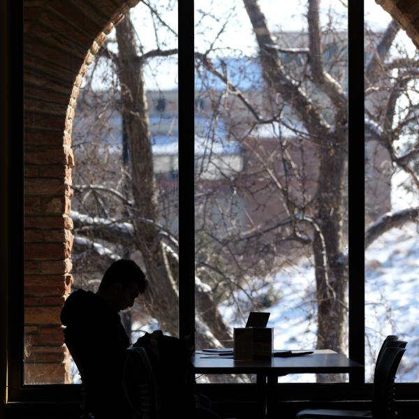 campus community member using a laptop with snow outside