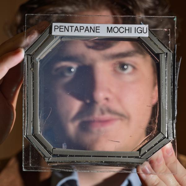 Man holds a block filled with clear material in front of his face