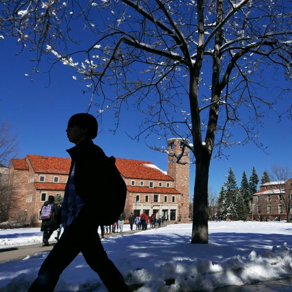 Student walks past Norlin Library in the snow