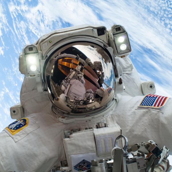 An astronaut is pictured in outer space with Earth in the background.