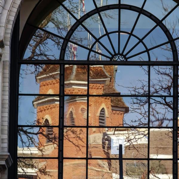 A reflection of Old Main in an arched window on campus.
