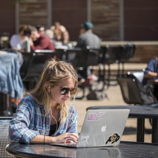 Student works on laptop in the UMC fountain area.