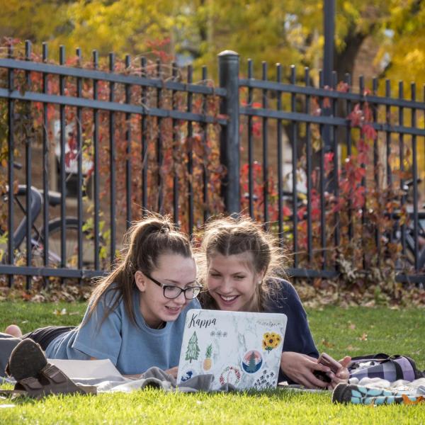 two students working at a laptop together outside