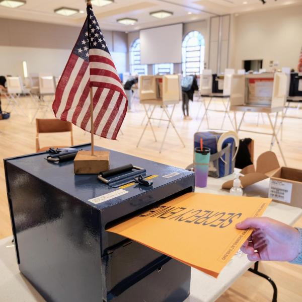 person drops ballot in a box