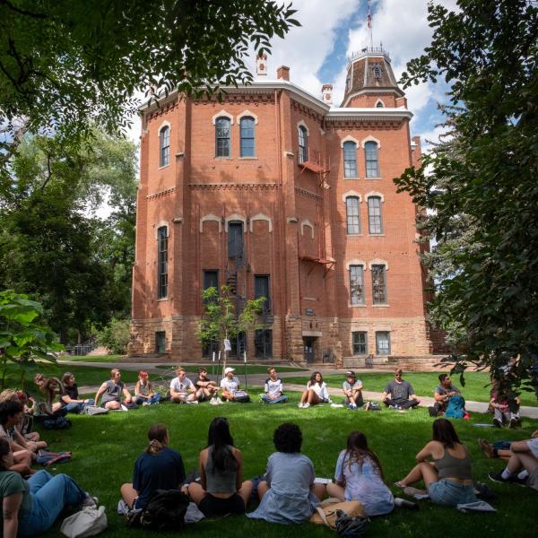 Students sit in a circle in the grass